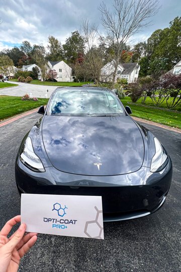 Extremely shiny ceramic-coated grey tesla Model 3 sitting in driveway