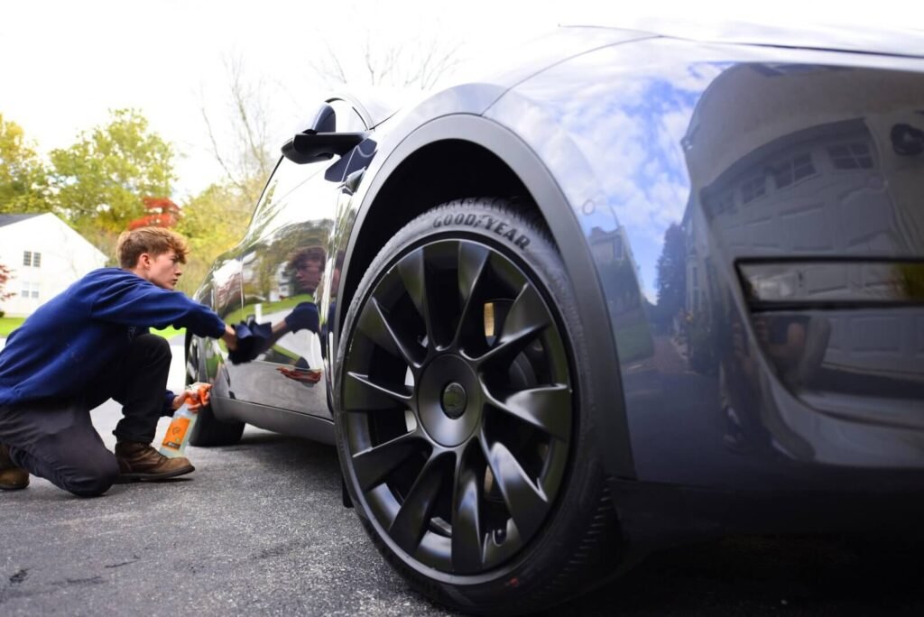 A guy using microfiber towel on very shiny grey tesla model 3